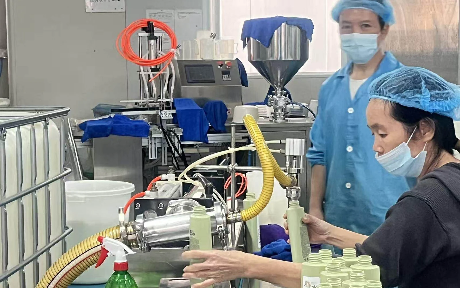 Technicians filling cosmetic bottles at a production station